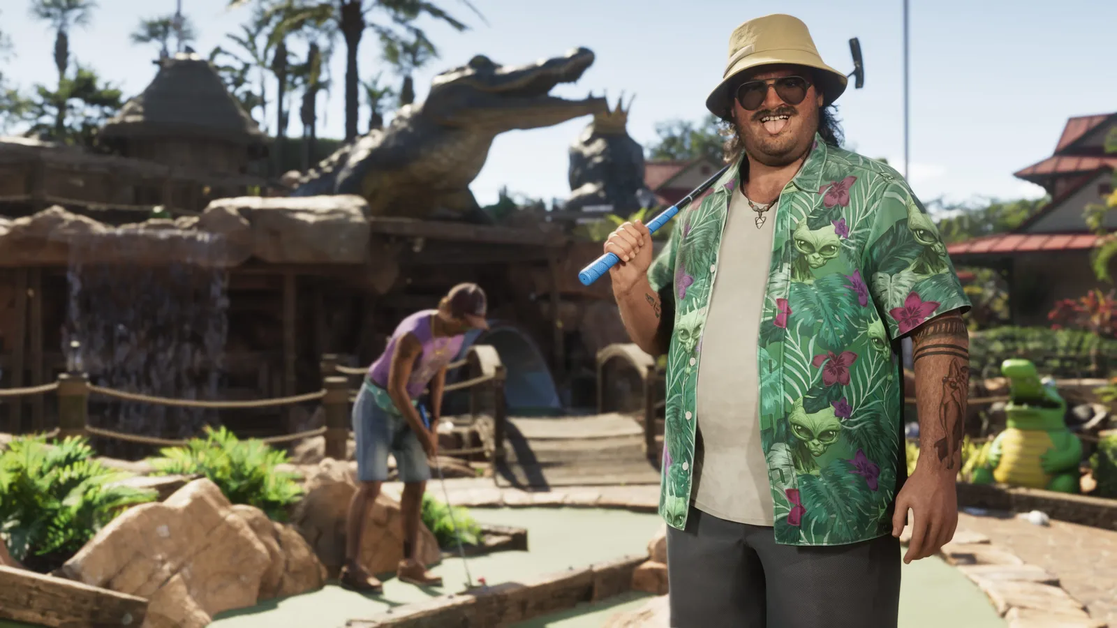 Cal Hampton in a bucket hat and a green floral shirt holds a golf club on a mini golf course decorated with a giant alligator statue
