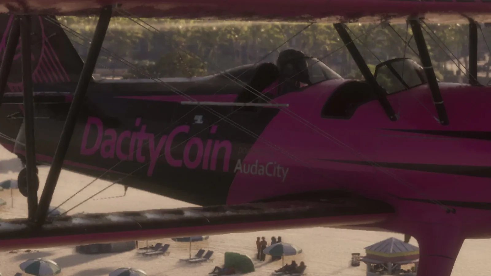 A pink biplane with DacityCoin and AudaCity painted on its side flies low over a crowded beach