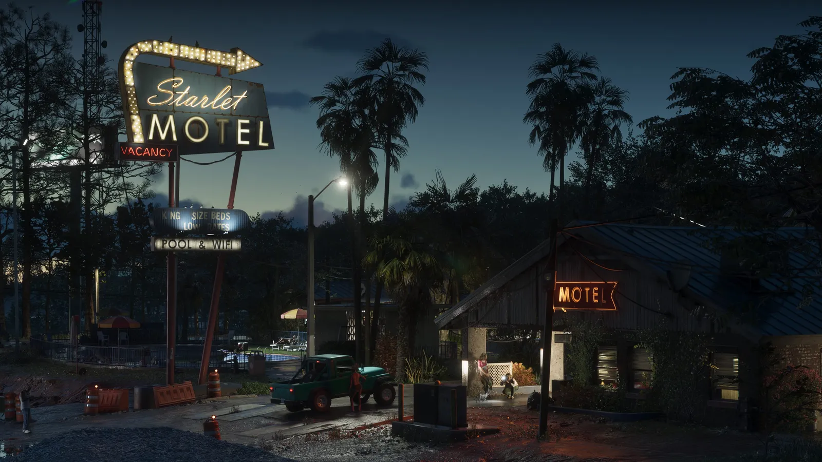 A quiet street at night with the neon sign of the Starlet Motel, palm trees and a parked pickup truck