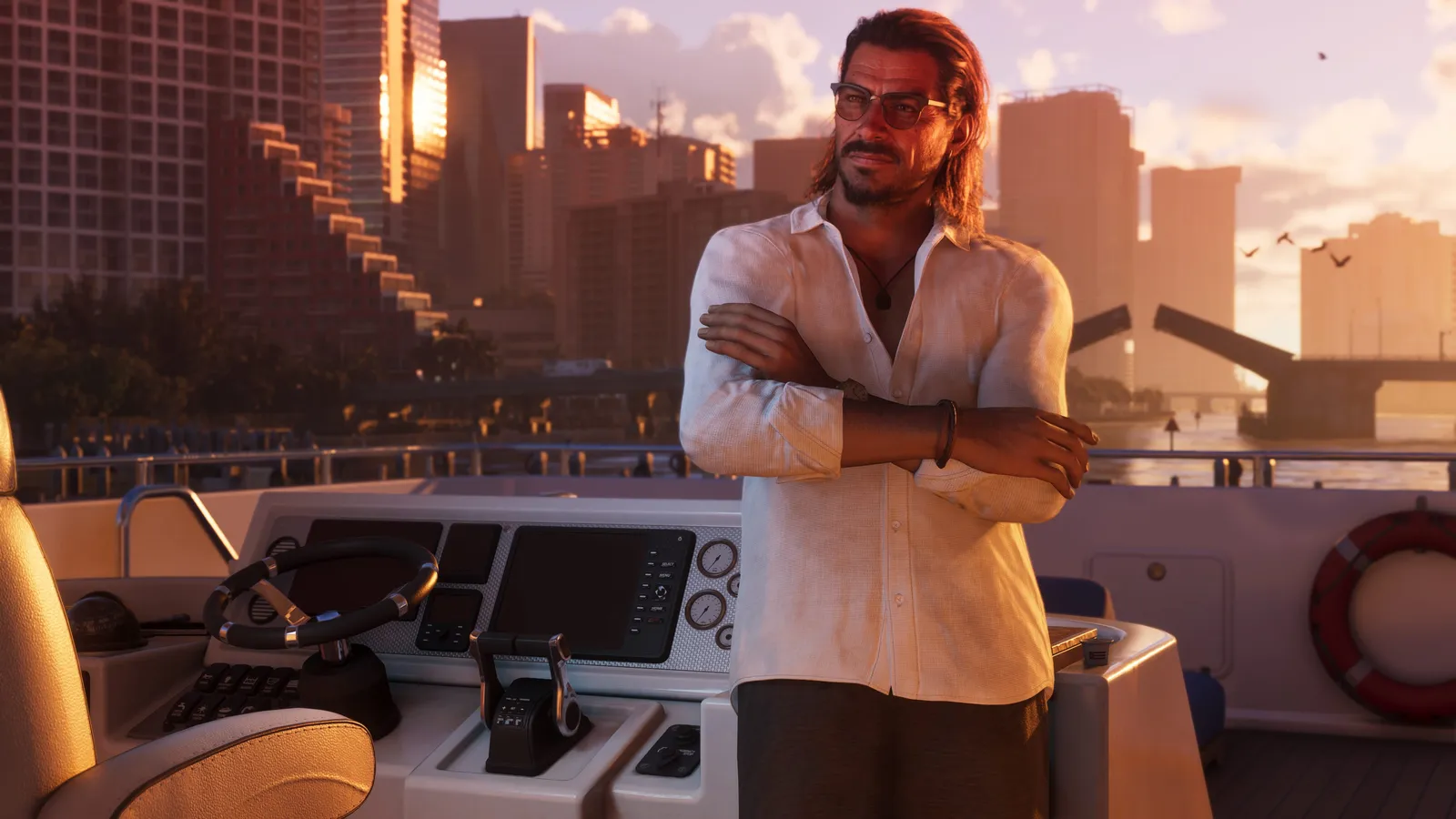 Raul Bautista, arms crossed, stands at the helm of a boat at sunset with a city skyline and a raised bridge behind him