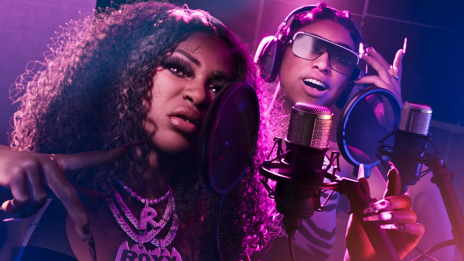 Real Dimez rapping into studio microphones with headphones on, in a purple-lit recording booth