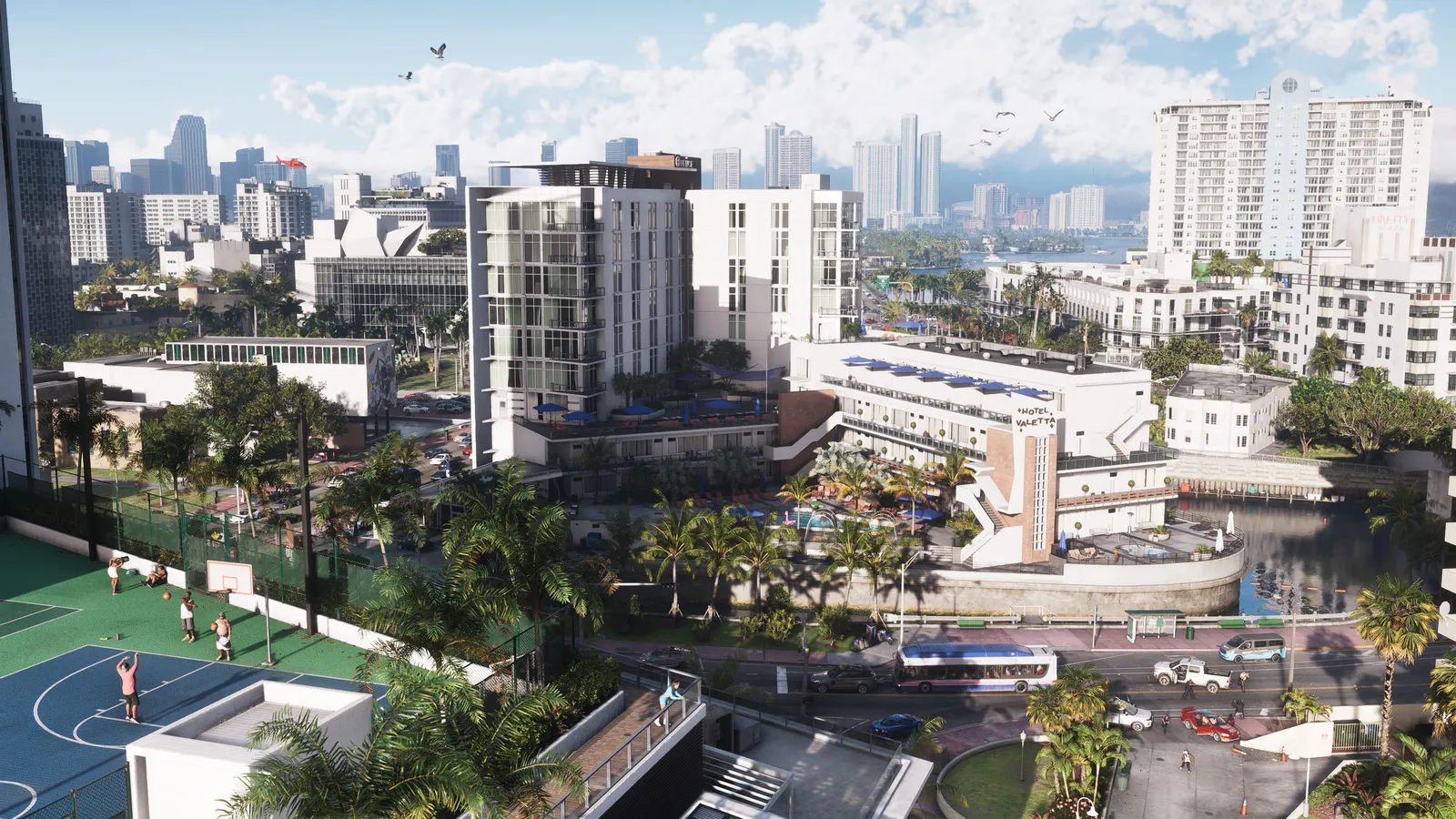 A sunny aerial view of Vice City: a basketball court, low-rise hotels, a canal and palm trees in front of a downtown skyline